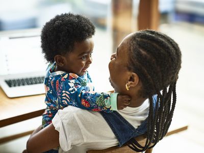 Woman holding baby while they look at each other smiling