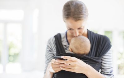 A picture of a mother kissing her baby and uploading something on social media