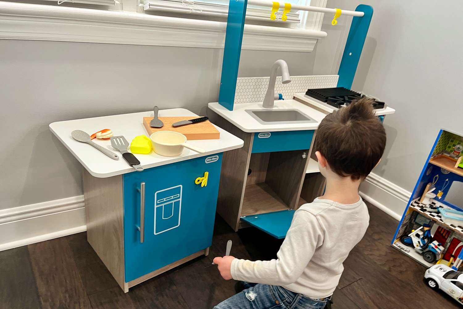 Toddler playing with Little Tikes Real Wood Kitchen with Island displayed on floor