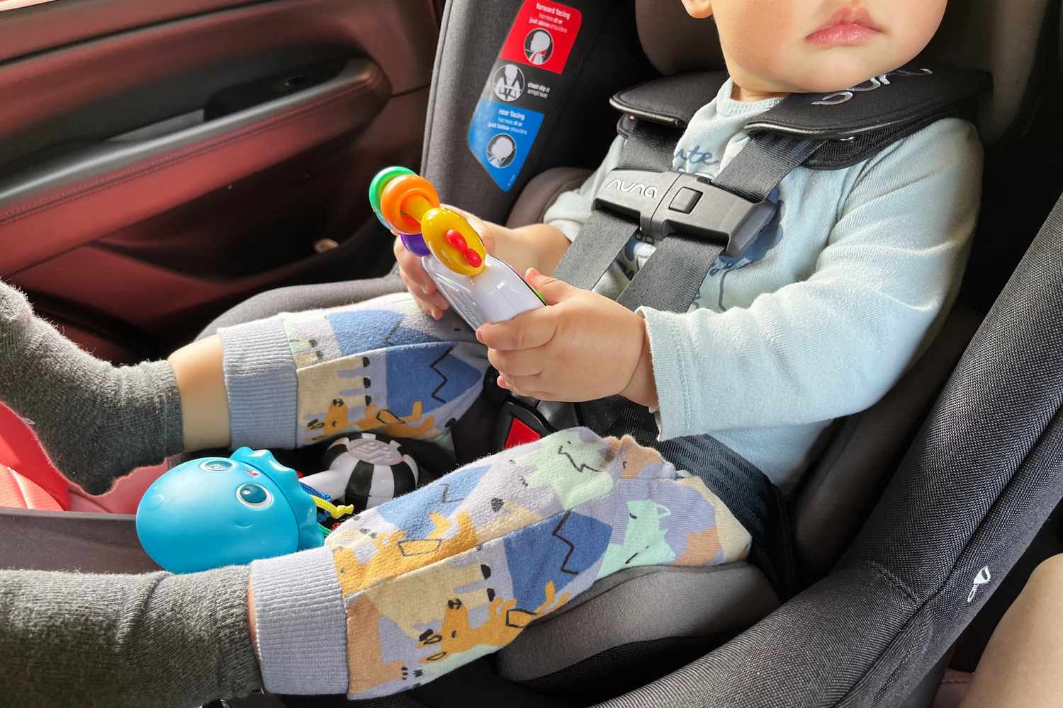 A child sits in the Nuna REVV Rotating Convertible Car Seat