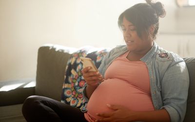 一个孕妇坐在家里的客厅里发短信