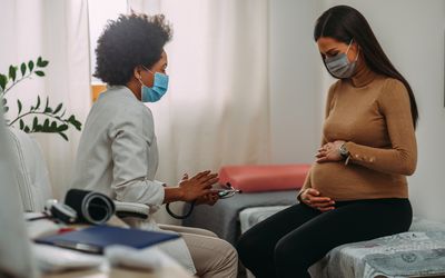 Doctor with a pregnant person in medical masks during an examinations.