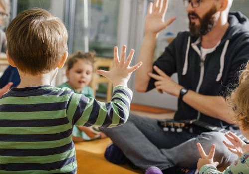 幼儿在与他人及老师一起唱歌时举手示意