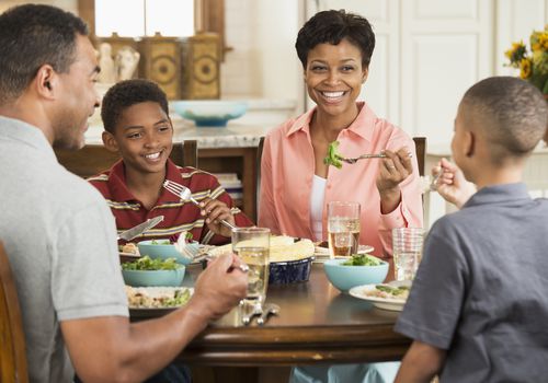 Family eating dinner together, talking and smiling