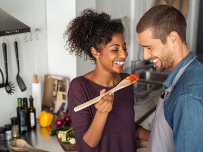 Multiethnic couple tasting fertility-boosting food from wooden spoon