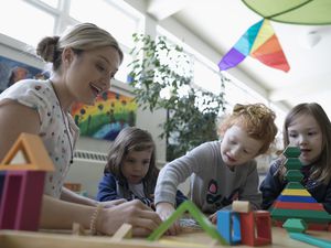 幼儿园老师和女学生在教室里玩积木