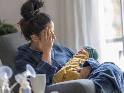 Tired new mother holding her baby - Stock Image