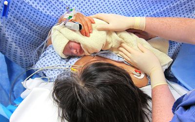 剖宫产后，母亲抱着婴儿在手术室里