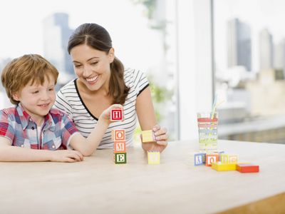 A picture of a mom and child playing a learning game with blocks