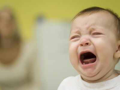 Baby crying, mother in background