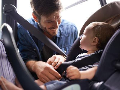 Father putting baby in car seat