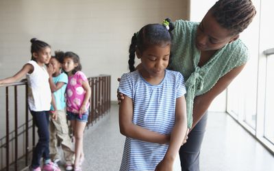 An image of a bullied child comforted by an adult.