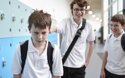 A boy being bullied by classmates in a school hallway