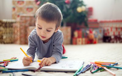 A young boy draws in a book.