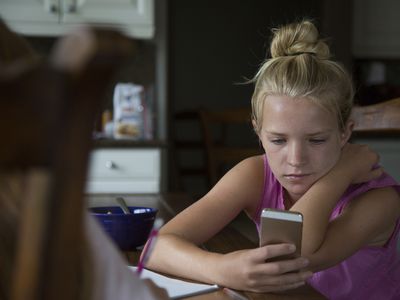 A young teenage girl looks at her phone.