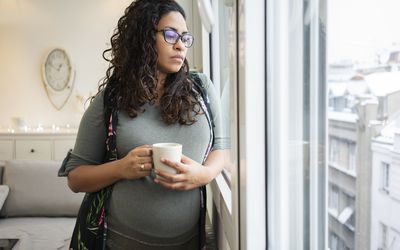 一个孕妇看着窗外喝咖啡
