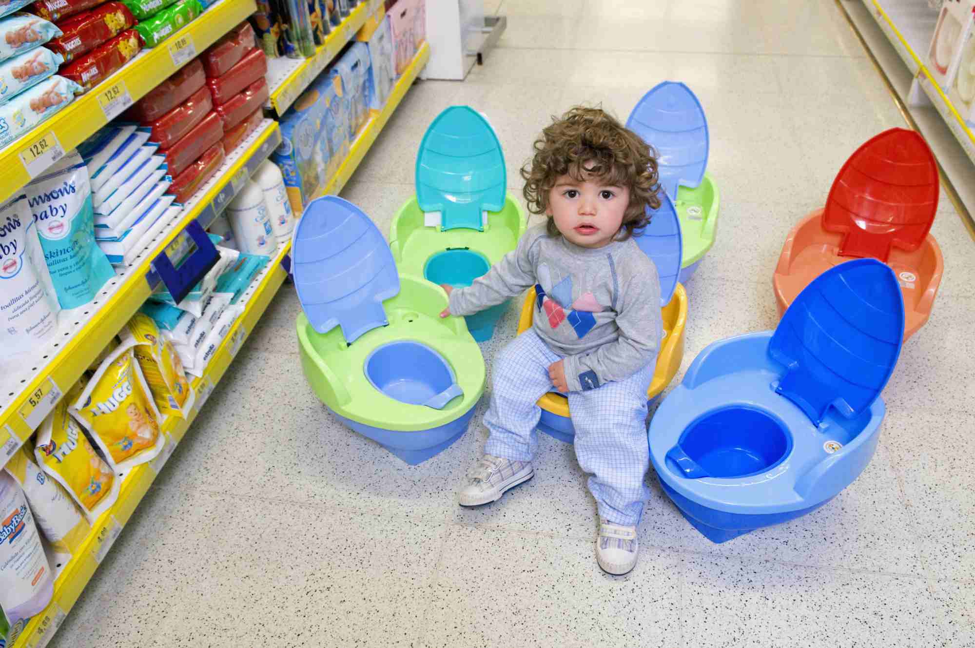 Baby boy sitting on a toilet bowl in a supermarket