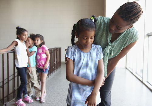 An image of a bullied child comforted by an adult.