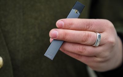 young adult holding a JUUL