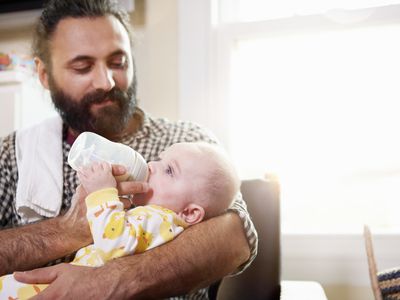 Father feeding baby with baby bottle