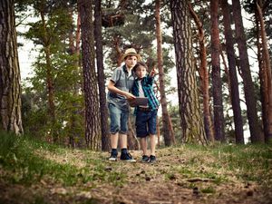 Boys with digital tablet in forest.