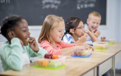 小学生们正坐在课桌前吃着健康的零食