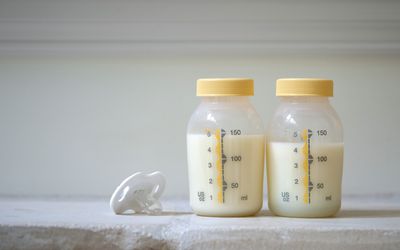 一个奶嘴和两个装满母乳的塑料瓶