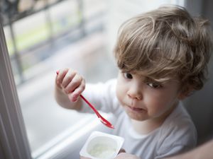 蹒跚学步的男孩吃酸奶，肖像