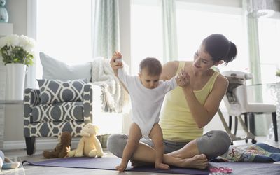 Mother playing with baby girl on exercise mat at home