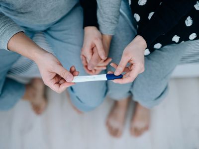 Couple holding hands and looking at a pregnancy test.