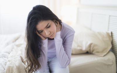 一个患有不孕症的抑郁妇女坐在床边