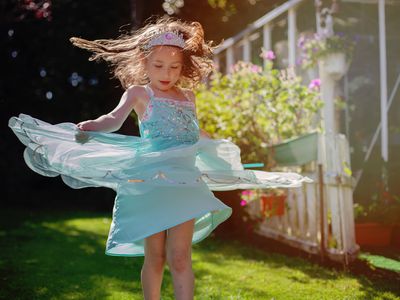 Girl wearing a princess dress dancing in a field