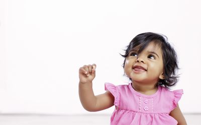 Baby girl in pink dress looking up