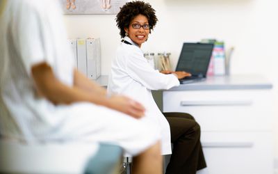 女医生在检查室用手提电脑与病人交谈，讨论人工受精程序