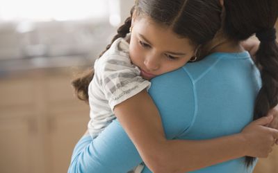 a mother holding her daughter in her arms＂width=