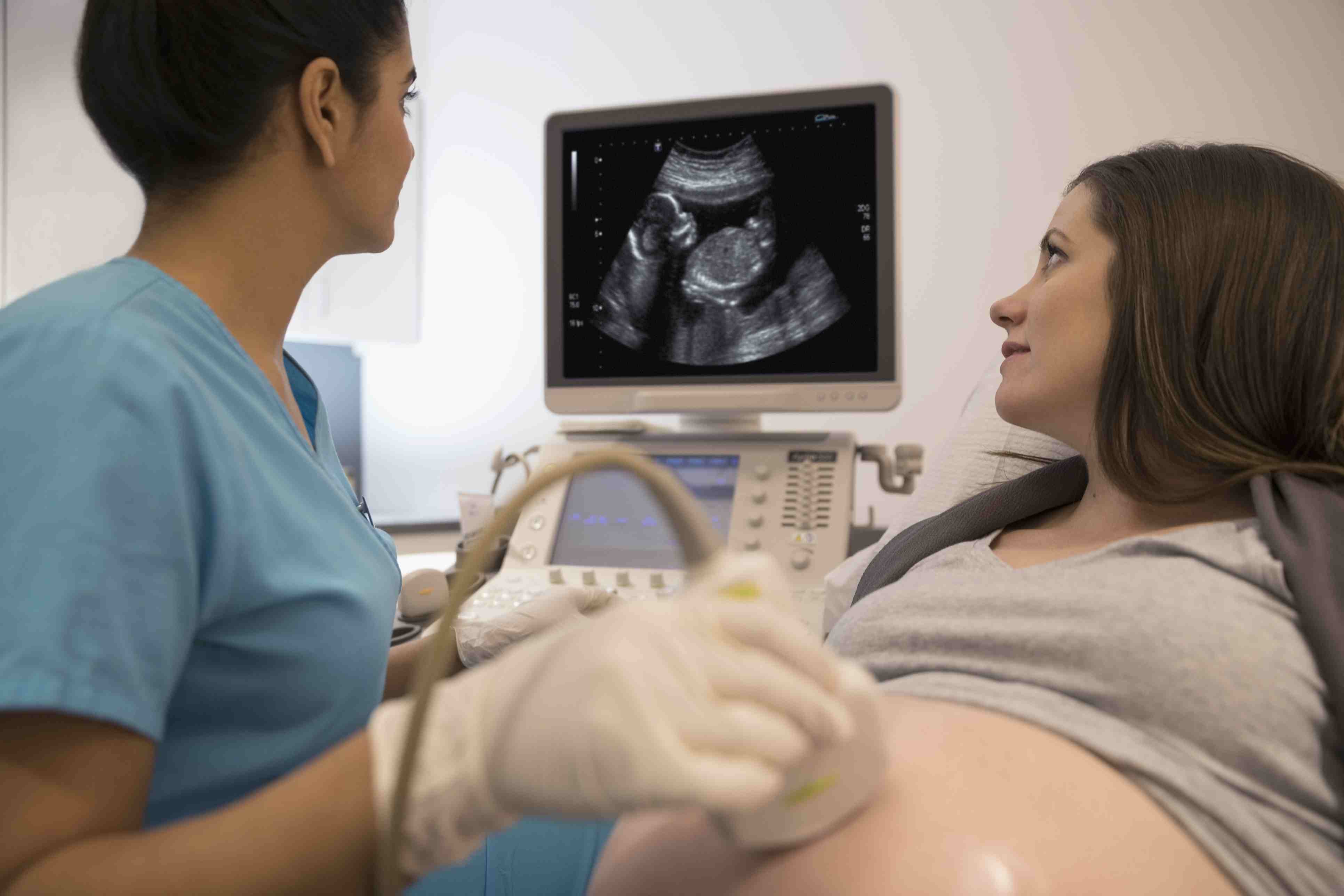 女护士在检查室为孕妇做超声检查