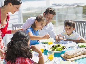 Family eating lunch at table on sunny patio