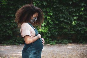 一个抱着肚子站在公园里的孕妇