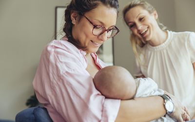 助产士扶着一位正在哺乳的母亲和她刚出生的婴儿