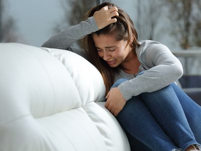 teen girl crying on couch