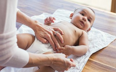 Mother changing baby's poopy diaper