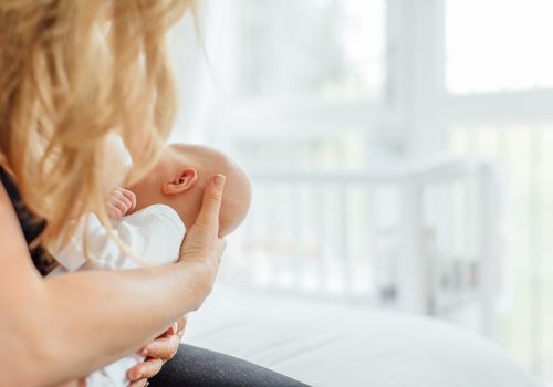 一名妇女在窗边哺乳她的婴儿