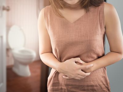 Pregnant person outside a bathroom experiencing stomach discomfort