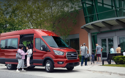 一辆红色的福特运输货车，载着父母和孩子们走进体育馆