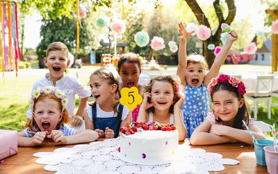 夏天，在花园的生日聚会上，孩子们围着桌子站着，手里拿着蛋糕