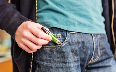 青少年从口袋里掏出电子烟