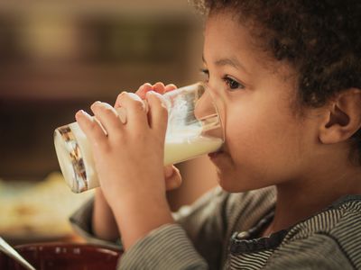 Little African American boy drinking fresh milk from a glass.