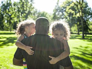 Father playing with twin daughters in park