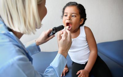 儿科医生检查女孩的嘴。