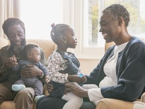 Grandparents holding a young girl and toddler boy in the living room